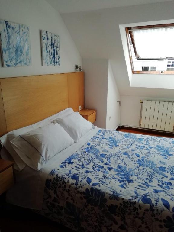 a bedroom with a bed with a wooden headboard and a window at Hospedaje Lopez in A Coruña