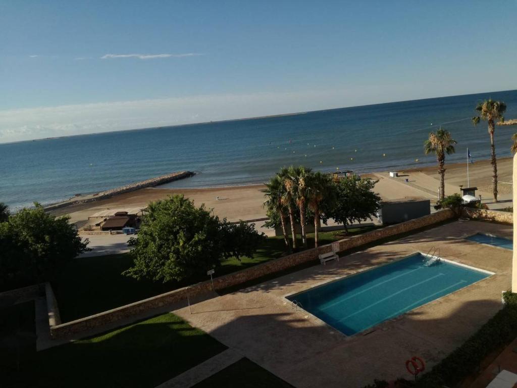 a view of a swimming pool and a beach at Atico primer linea de mar con piscina en EbreHogar in Sant Carles de la Ràpita