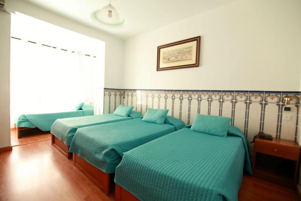 2 Betten in einem Zimmer mit blauer Bettwäsche in der Unterkunft Residencial Joao XXI in Lissabon