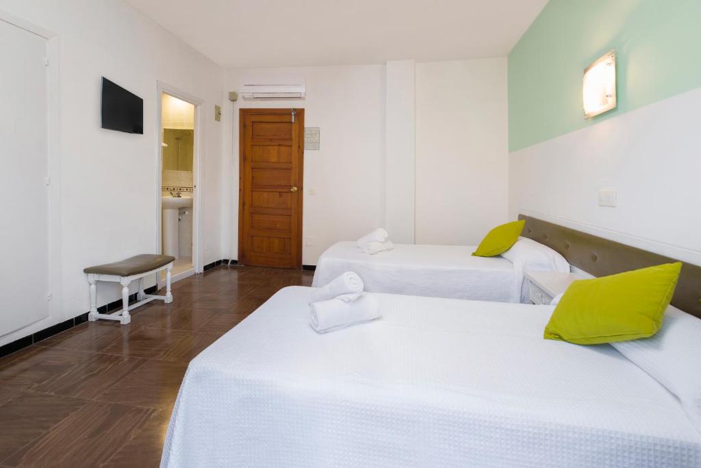 a room with two beds and a television at Hostal Alicante in San Antonio
