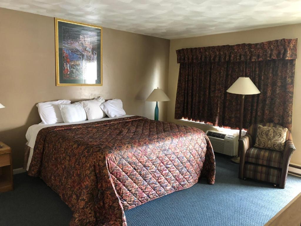 een hotelkamer met een bed en een stoel bij Village Inn Motel Holt in Holt
