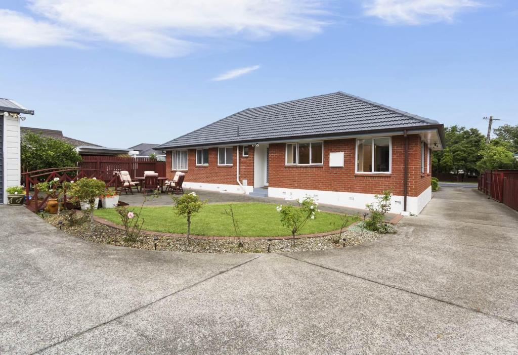 a red brick house with a garden in front of it at Auckland Airport Guest House in Auckland