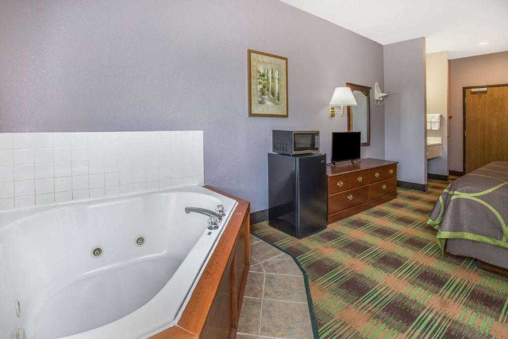 a hotel room with a tub and a bed at Super 8 by Wyndham Sweet Springs in Sweet Springs