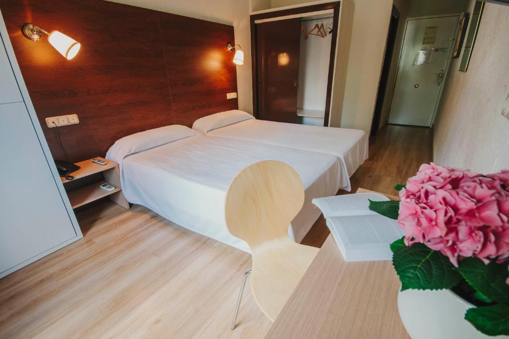 una camera con letto bianco e rose rosa di Hotel Embajador a Almería