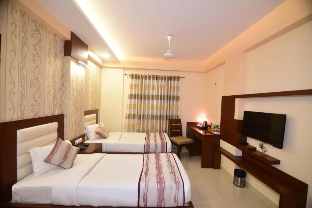 a hotel room with two beds and a flat screen tv at Hotel Varanasi Inn in Varanasi