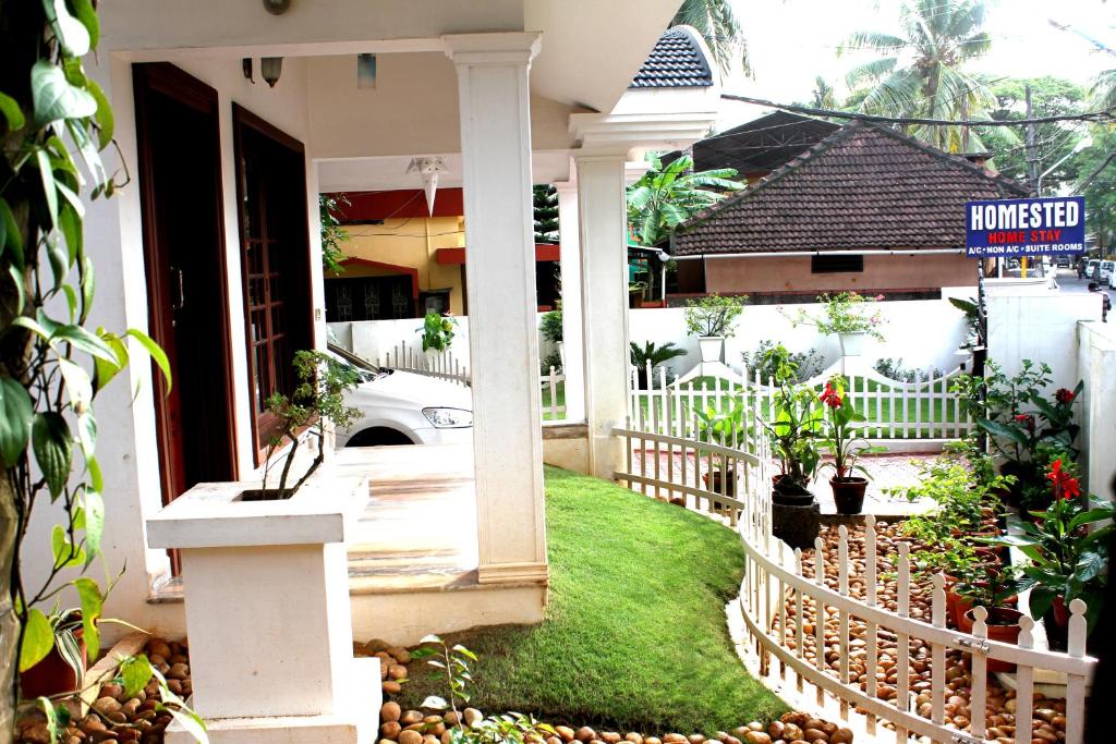 a house with a white fence and a yard at Homested Homestay Fort Kochi in Cochin