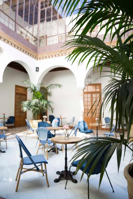 une chambre avec des tables, des chaises et un palmier dans l'établissement nüa santiago15, à Séville