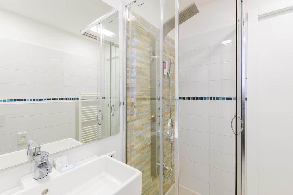 a white bathroom with a shower and a sink at Hotel Viking in Rimini