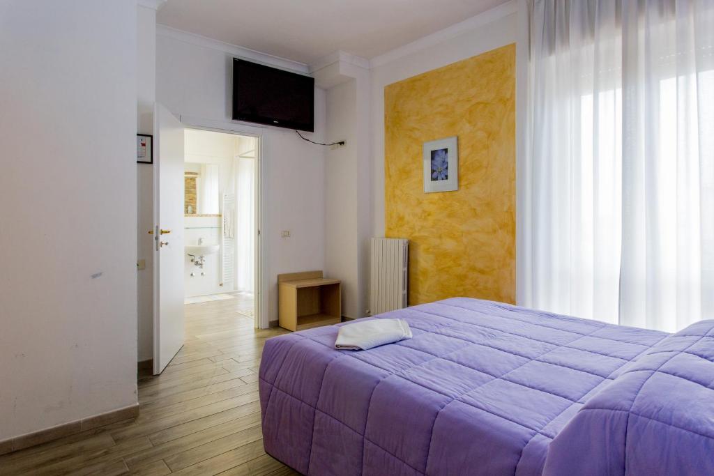 a bedroom with a purple bed and a window at Hotel Viking in Rimini