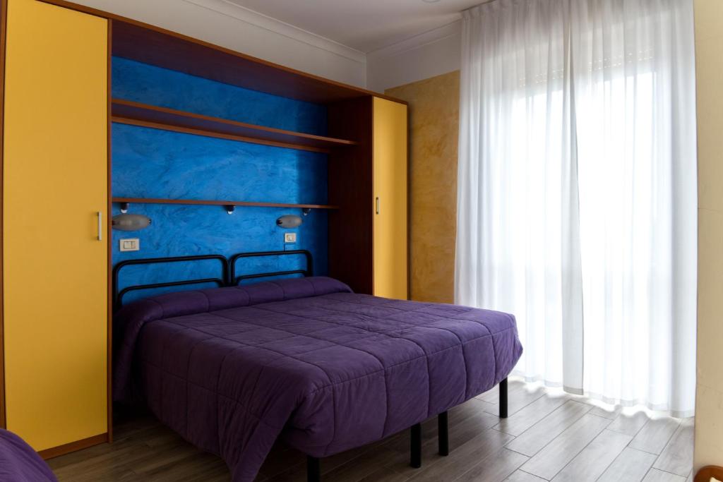a bedroom with a purple bed with a blue headboard at Hotel Viking in Rimini