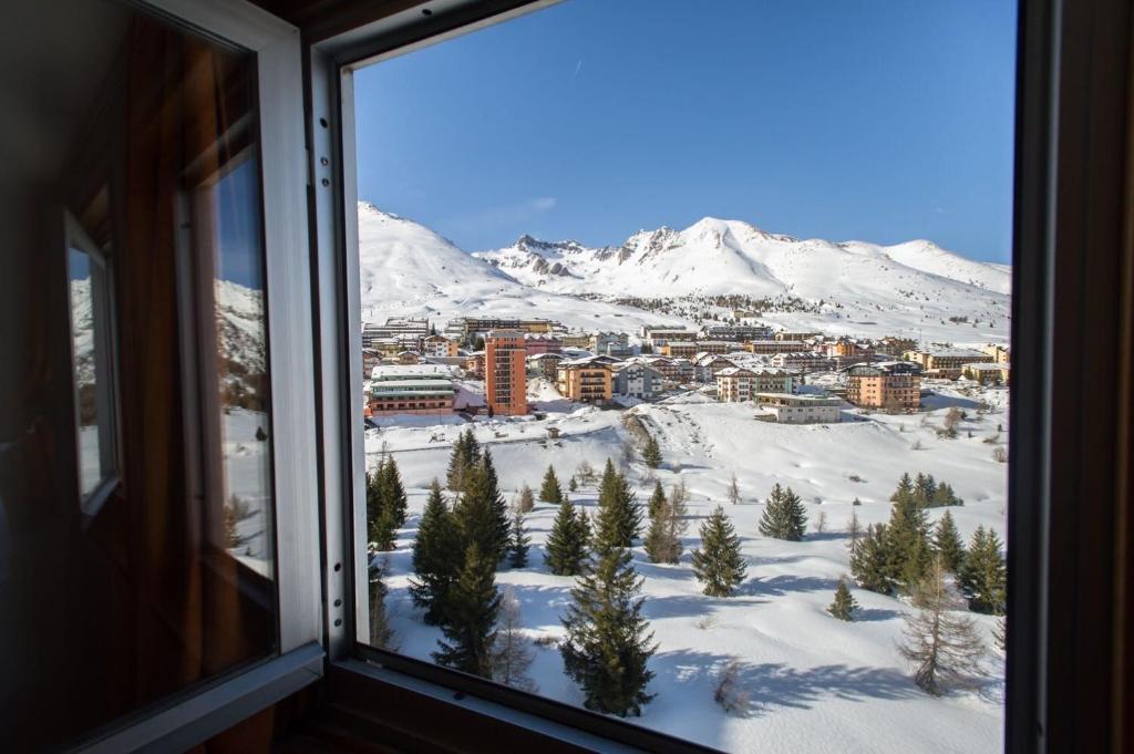 una vista da una finestra di una città nella neve di Appartamento Biancaneve a Passo del Tonale