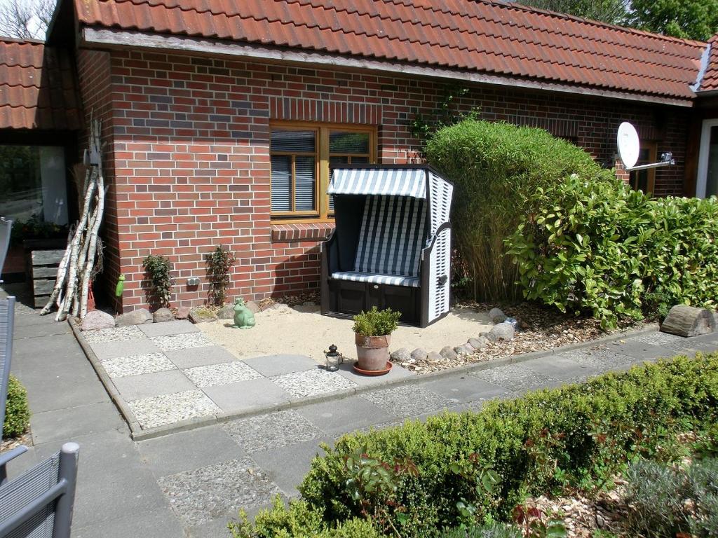 a brick house with a garden with a bench in front of it at Landhaus Pfahlershof in Karolinenkoog
