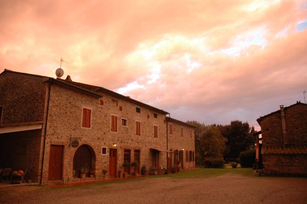 an old brick building with a cloudy sky in the background at Agriturismo Le Piane Del Milia in Suvereto