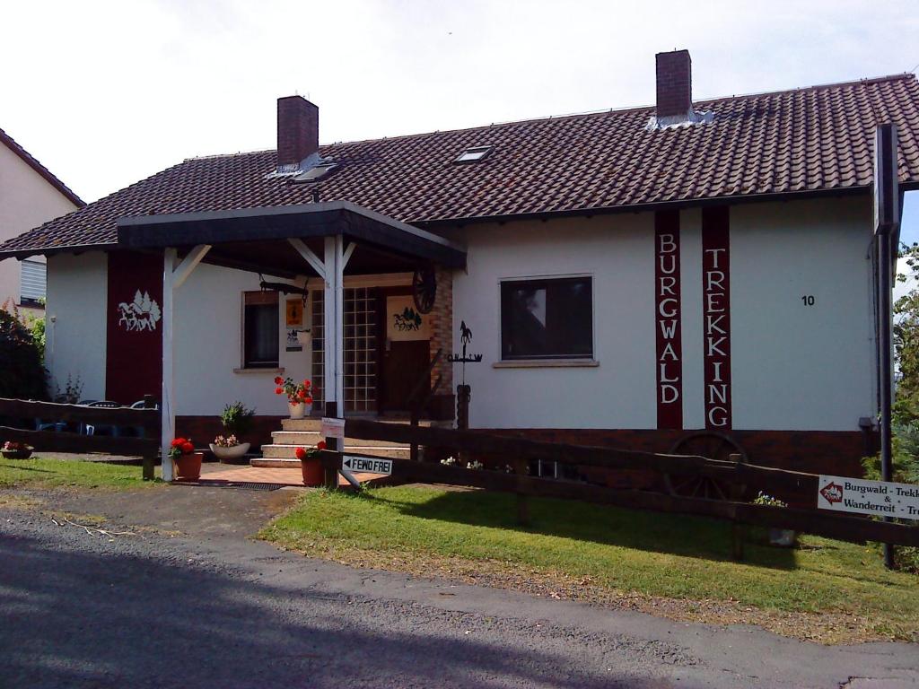 a small white house with a porch on a street at Gästehaus Burgwald-Trekking in Mittelsimtshausen