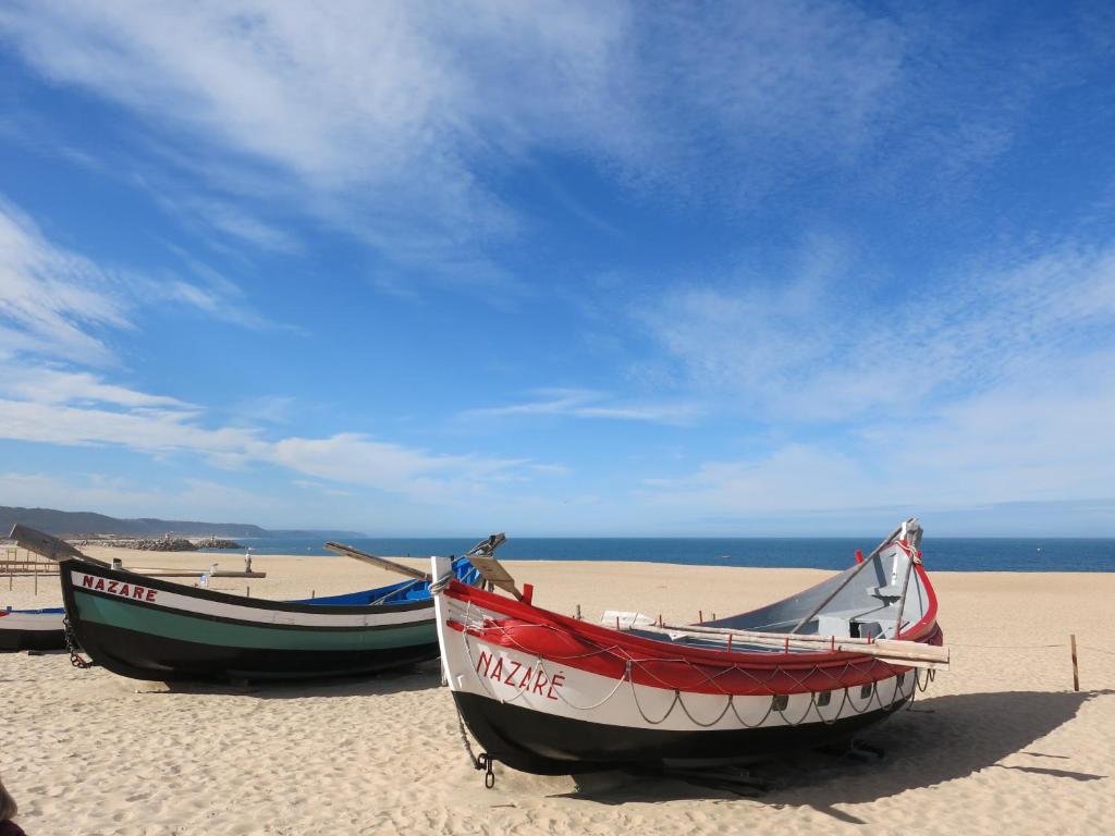 dois barcos sentados na praia numa praia em Serena Beach 2 na Nazaré