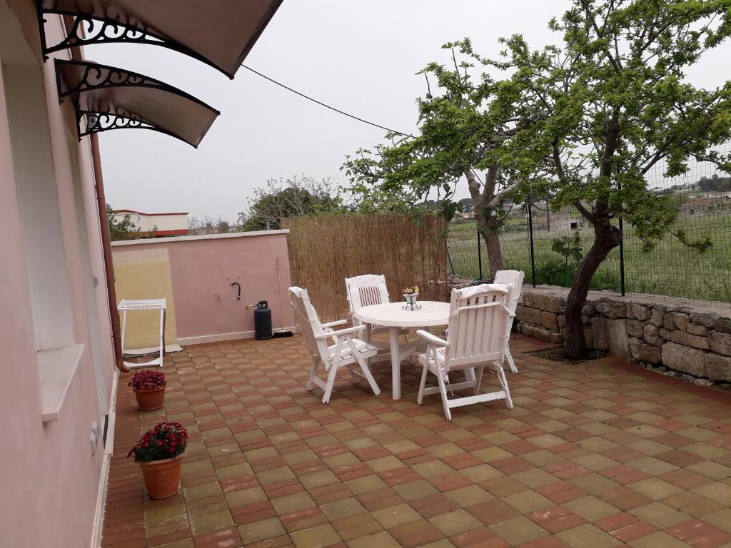 un patio con mesa, sillas y un árbol en Casa Vacanza Campoli, en Ruffano