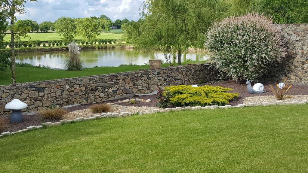 un jardin avec un mur en pierre et un étang dans l'établissement La Turlure, à Bressuire