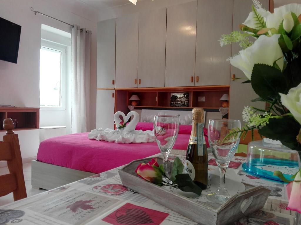 a bedroom with a pink bed with a table with wine glasses at La Necussella in Anacapri