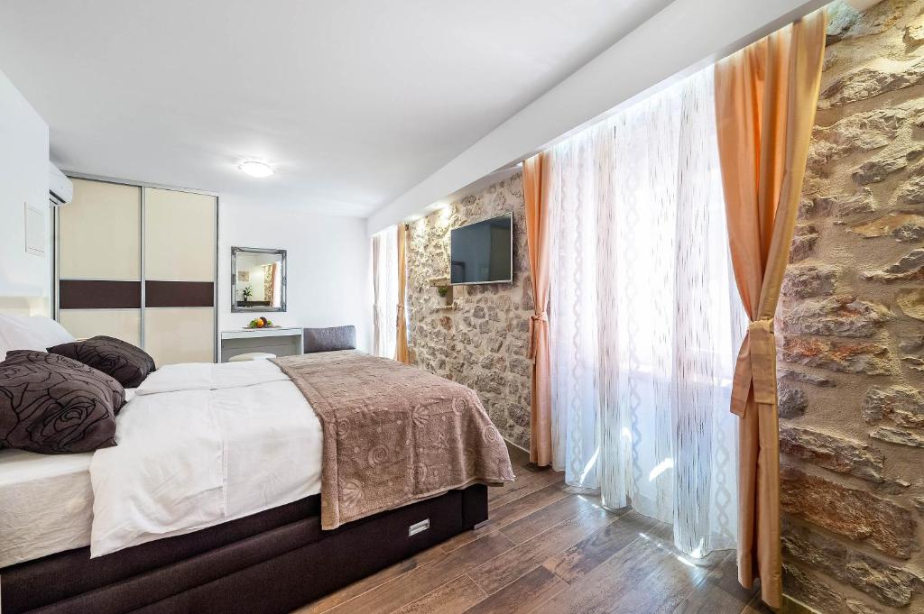 een slaapkamer met een bed en een stenen muur bij Apartments Palace Rialto in Šibenik