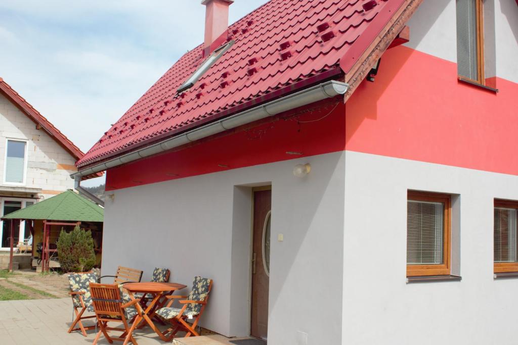 een rood-wit huis met een tafel en stoelen bij Petúnia-dom s dvoma spálňami in Bešeňová