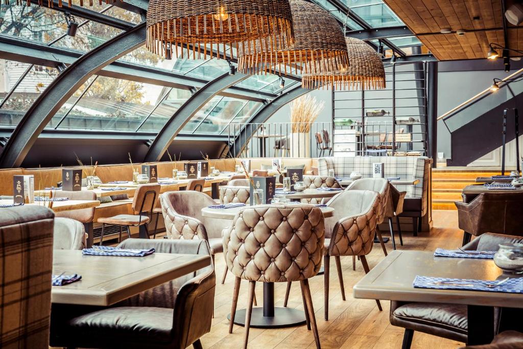 a restaurant with tables and chairs and a chandelier at Hotel Meersinn klimaneutral in Binz