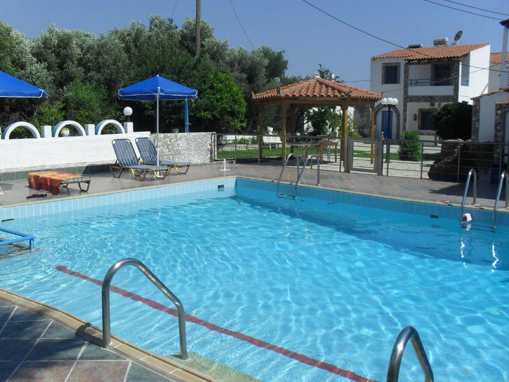 a large blue swimming pool with chairs and a gazebo at Chris Apartments in Marathokampos