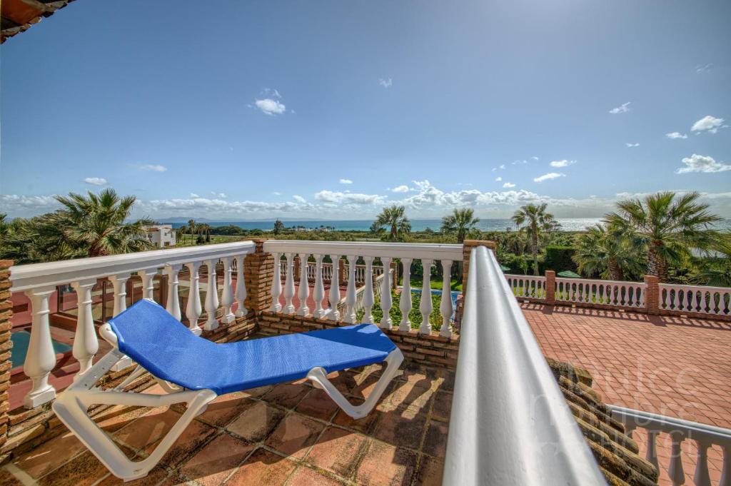 a blue chair sitting on a balcony overlooking the ocean at Dulce Nombre Hotel - Apartamentos in Tarifa