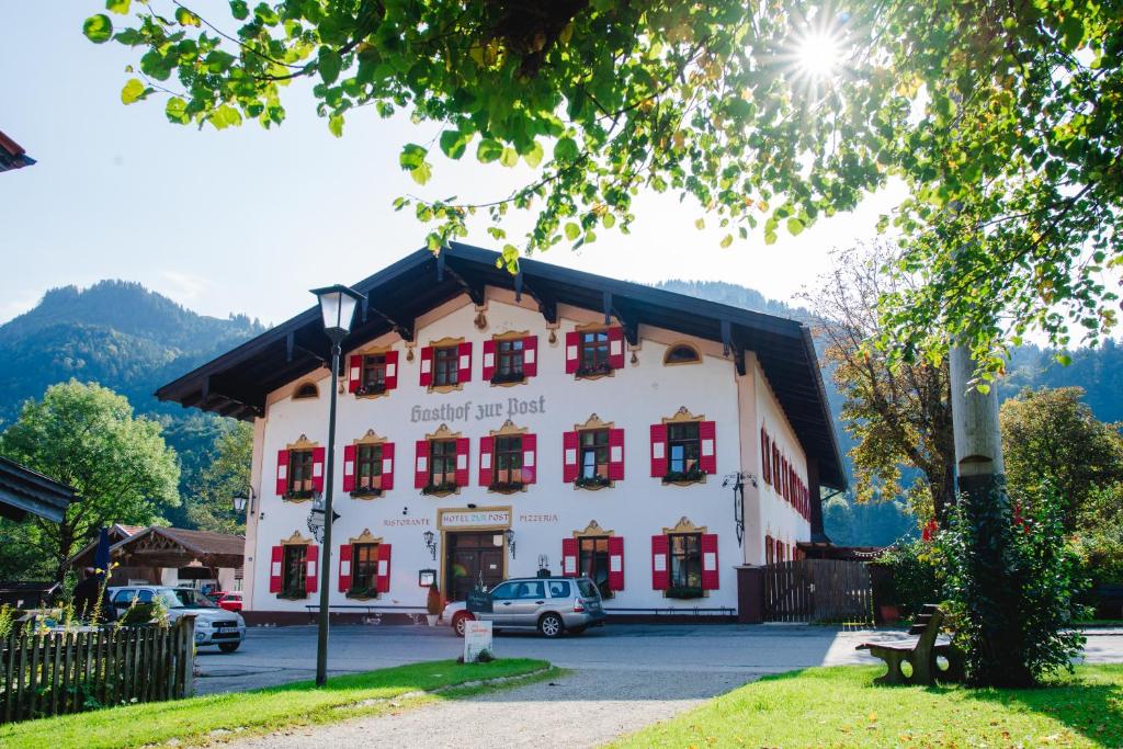 a large white building with red shuttered windows at Posthotel Sachrang in Sachrang