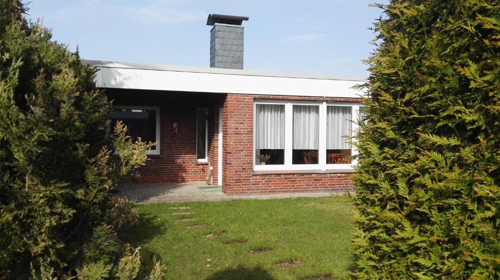 una casa de ladrillo vista a través de un seto en Haus Antje, en Norddeich