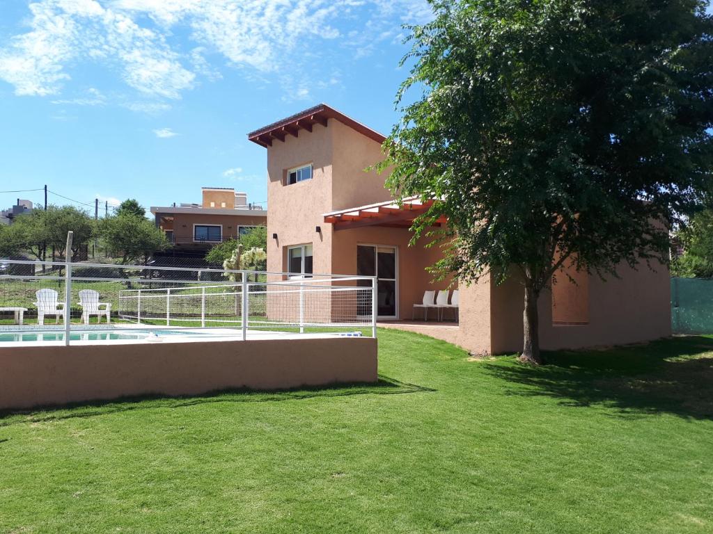 una casa con un patio con un árbol y una valla en Kawsay Complejo de Cabañas en San Antonio de Arredondo