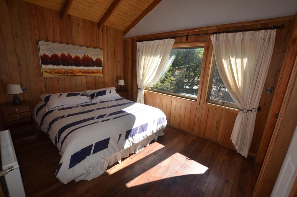 a bedroom with a bed and a large window at Cabañas Las Cabras in Las Trancas