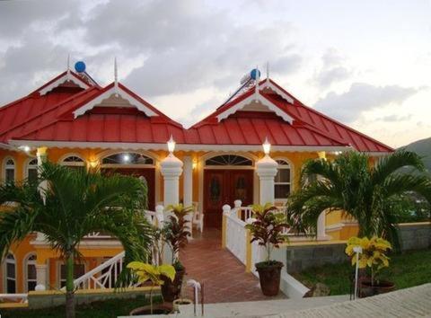 une maison avec un toit rouge et des palmiers dans l'établissement Paradise Cove, à Gros Islet