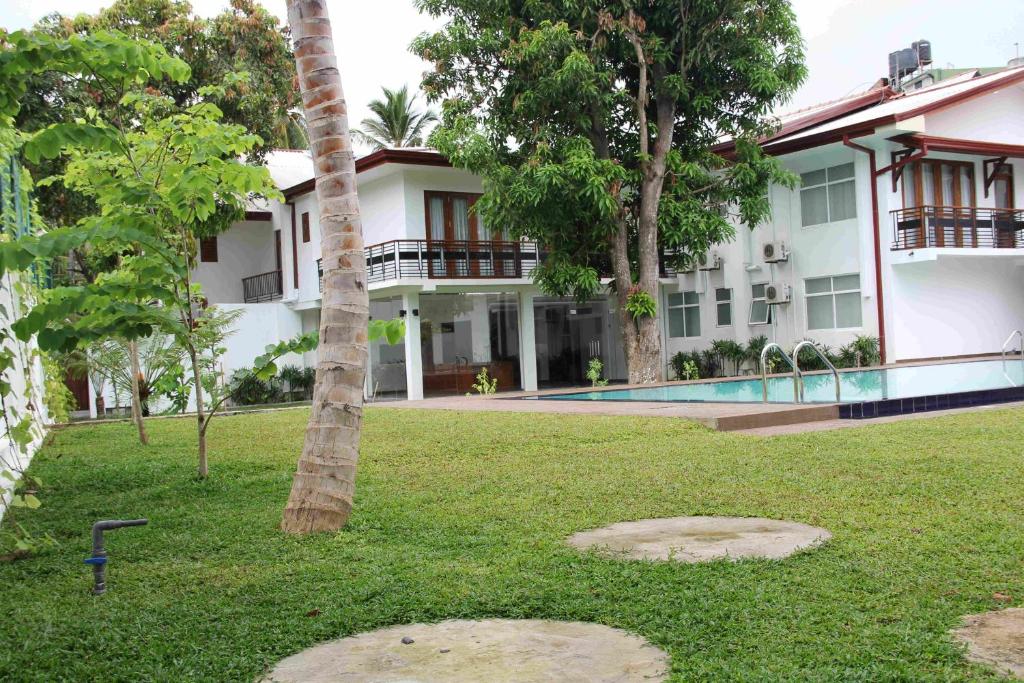 a building with a palm tree in front of a yard at Serenity Tissa in Tissamaharama