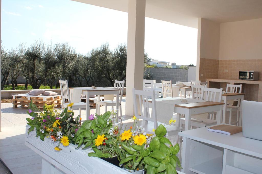 un patio con mesas blancas, sillas blancas y flores en Piccolo Ulivo B&B Salento, en Vernole