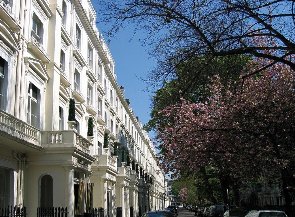 a city street with white buildings and a flowering tree at Caesar Hotel in London