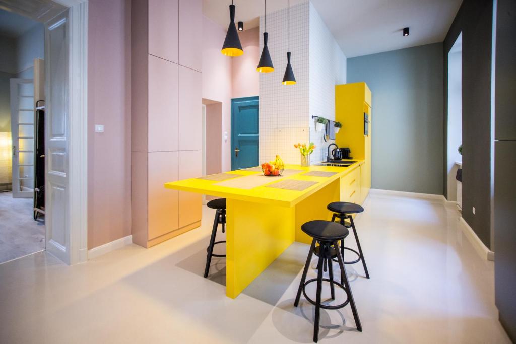 a yellow island in a kitchen with stools at Posh Loft in the Centre in Budapest