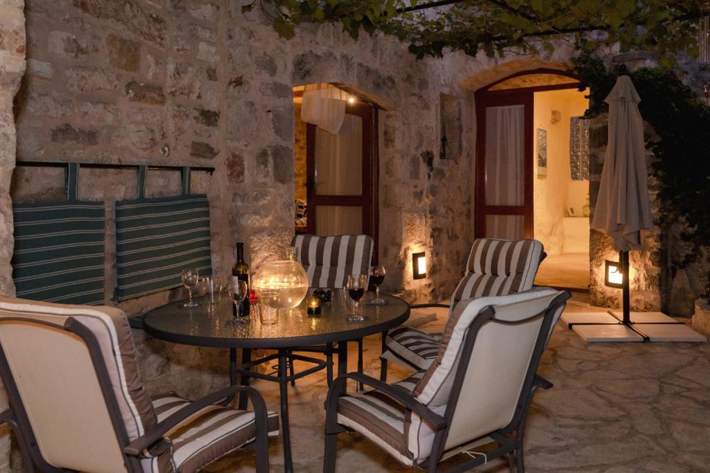 un patio con mesa, sillas y sombrilla en Stone House and Cottage Clio en Vrbanj
