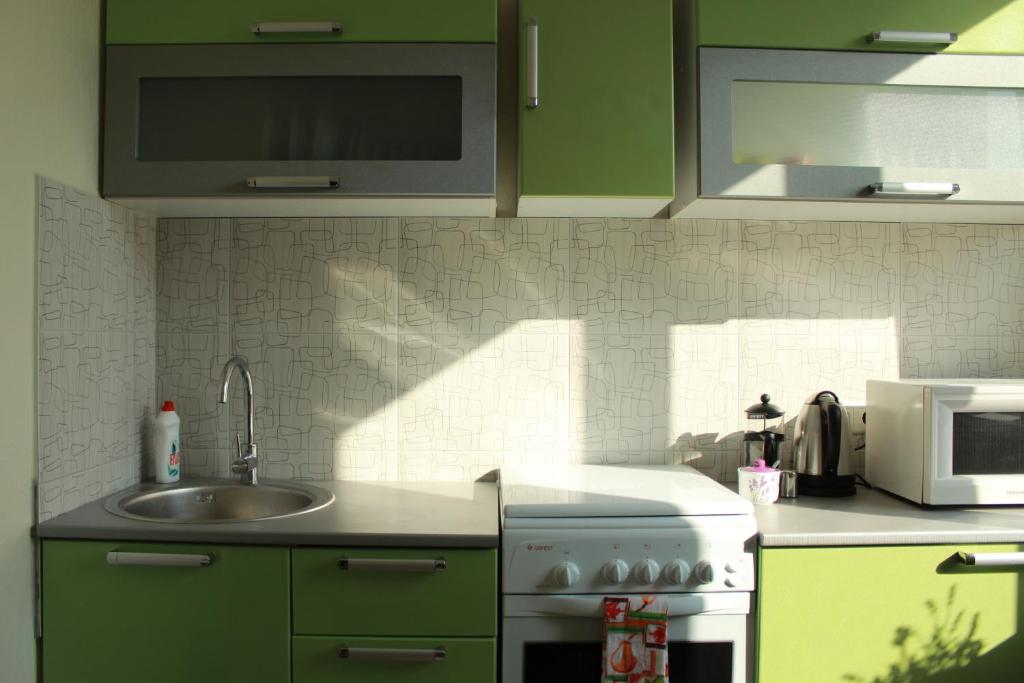 a kitchen with green cabinets and a sink and a microwave at Happy Day in Narva