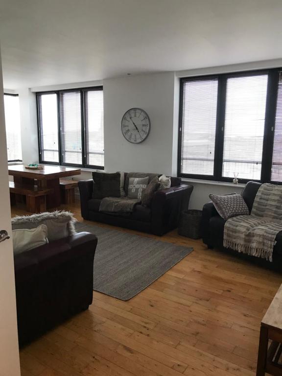 1 Farnsby Street Apartment 19 في سويندون: غرفة معيشة مع أريكة وساعة على الحائط