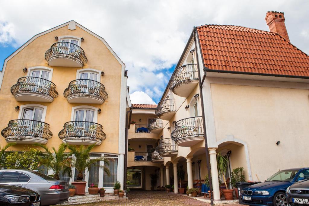 a building with balconies and cars parked in a parking lot at Villa Mediterran in Hévíz