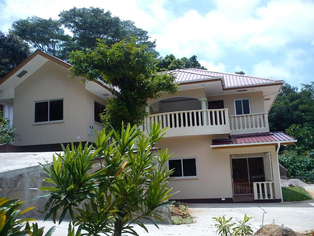 ein Haus mit einem Balkon und einem Baum in der Unterkunft Zeph self catering in Baie Lazare, Insel Mahé