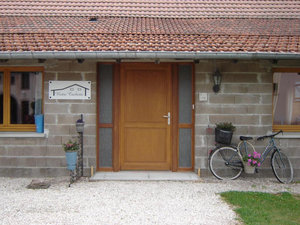 uma bicicleta estacionada em frente a uma casa com uma porta de madeira em Notre Cachette em Biffontaine