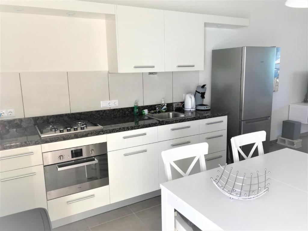a kitchen with white cabinets and a stainless steel refrigerator at Blije Rust 10 in Willemstad