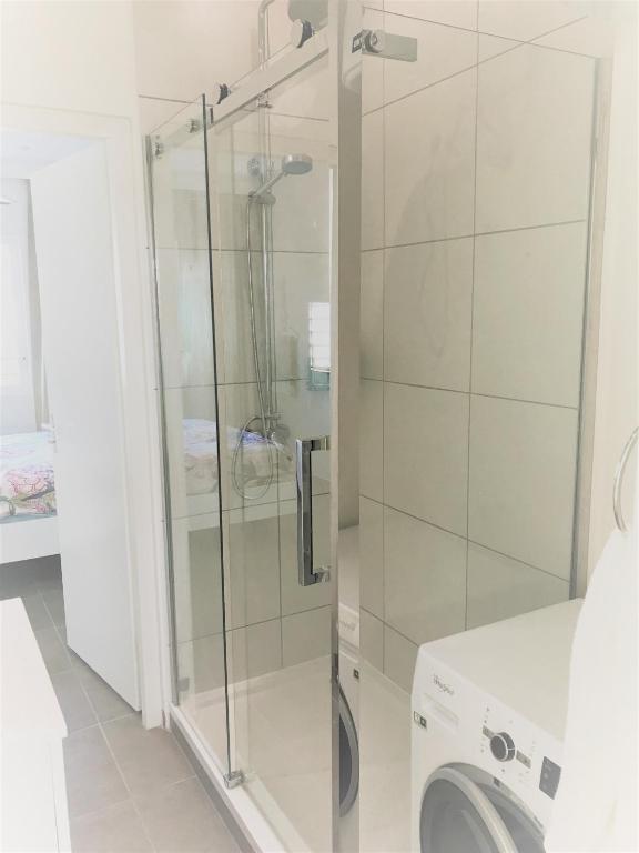 a glass shower in a bathroom with a washing machine at Blije Rust 10 in Willemstad