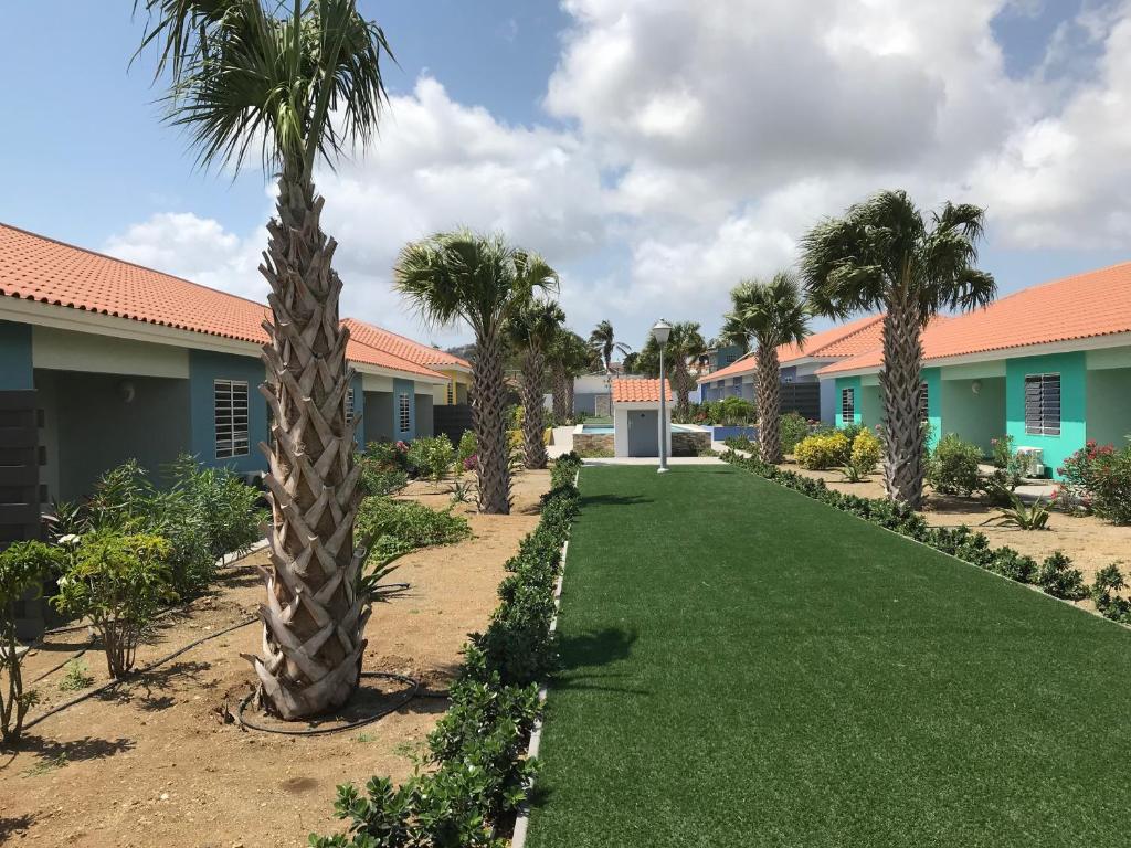 a yard with palm trees and houses at Blije Rust 10 in Willemstad
