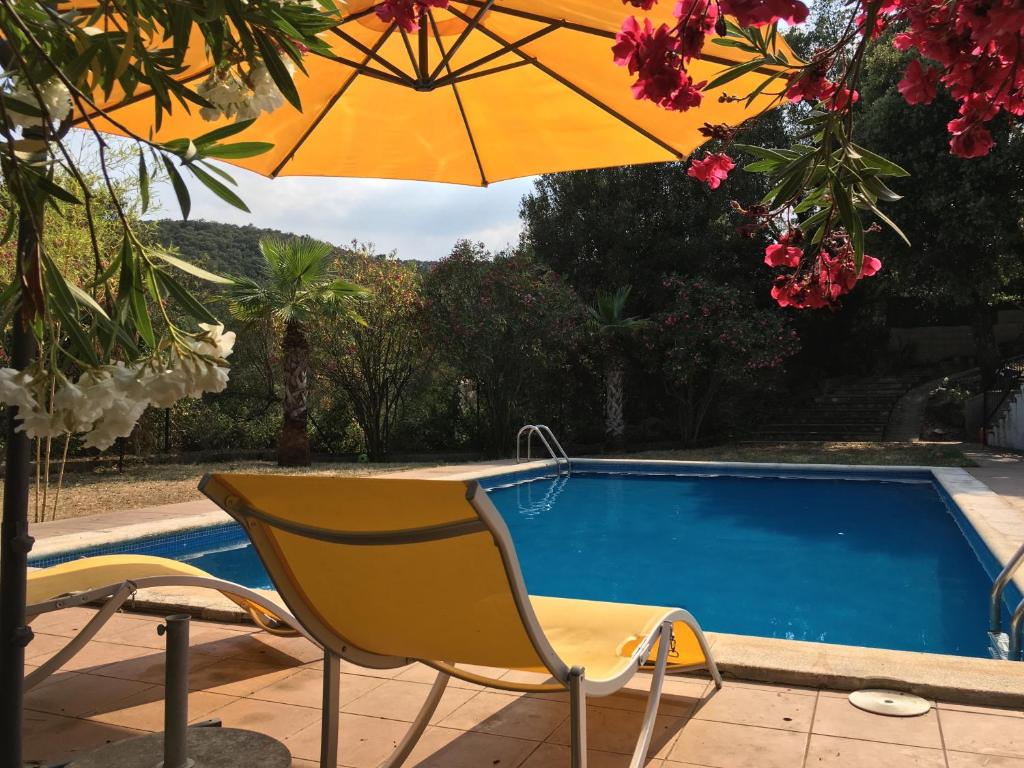 een gele stoel en een parasol naast een zwembad bij Villa for eight guests in San Ciprián dels Alls