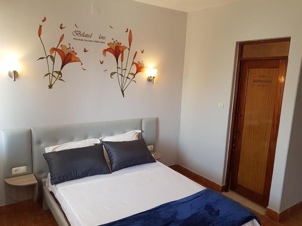 a bedroom with a bed with flowers on the wall at Pensão Asa Branca in Assomada