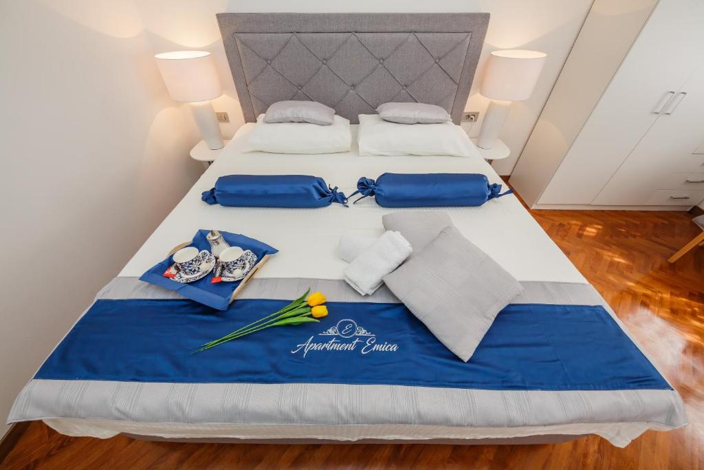 a bed with blue and white sheets and pillows on it at Apartment Emica in Split