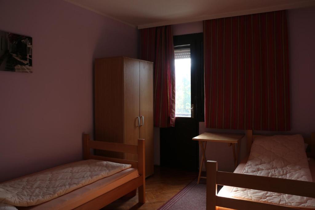 a bedroom with two beds and a cabinet and a window at Hostel Trajan in Donji Milanovac