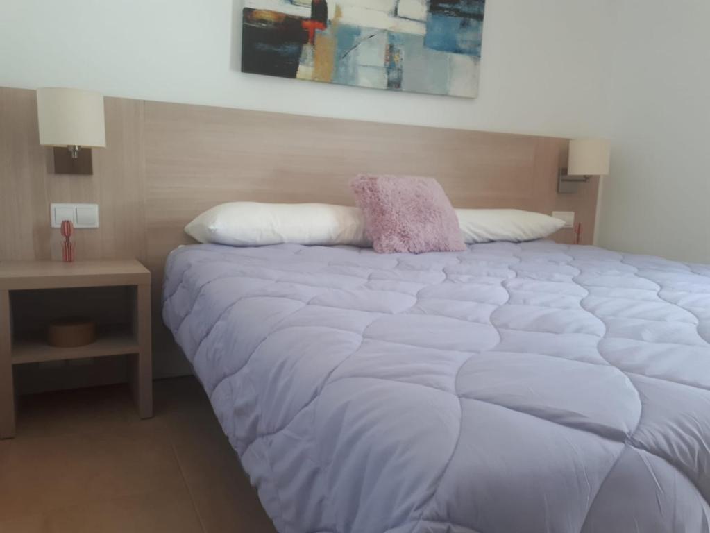 Una cama blanca grande con una almohada rosa. en Fuerteventura Port Sea, en Morro del Jable